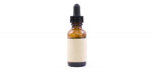 Amber glass serum dropper bottle with a blank cream label on a white background