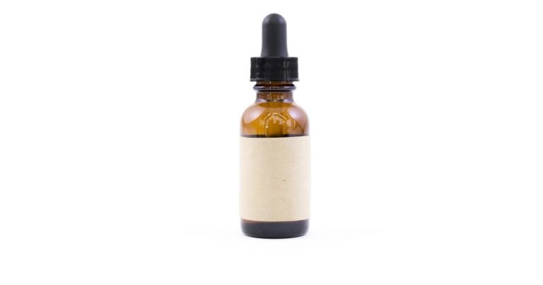 Amber glass serum dropper bottle with a blank cream label on a white background