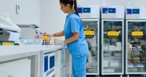 Laboratory technician in blue scrubs processing samples in a clinical pathology laboratory
