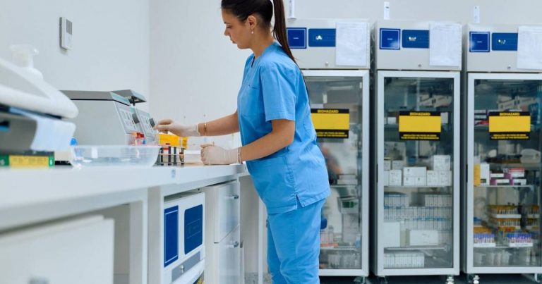 Laboratory technician in blue scrubs processing samples in a clinical pathology laboratory