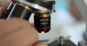 Close up of a microscope objective lens positioned over a specimen slide in a laboratory