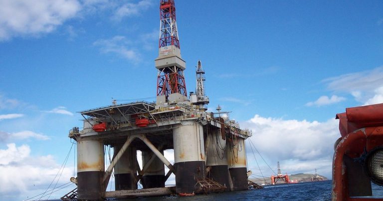 Semi submersible offshore drilling rig with its derrick standing against a blue sky and open sea