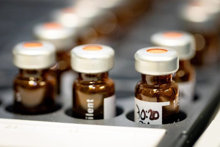 Row of amber glass sample vials with crimped caps in a laboratory analyzer tray