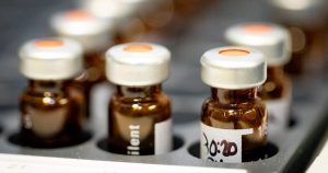 Row of sealed amber vials with crimped caps in a laboratory tray, ready for reconstitution