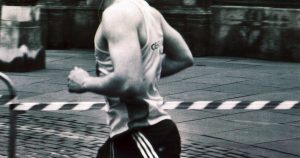 Runner in athletic clothing captured mid stride on a city street in black and white