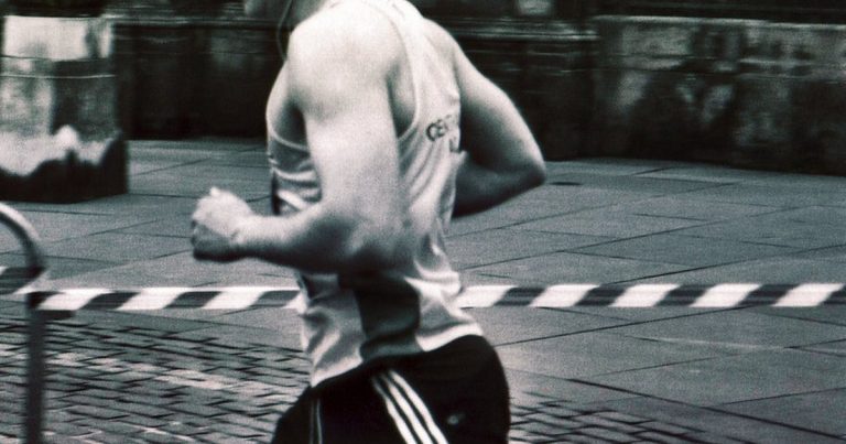 Runner in athletic clothing captured mid stride on a city street in black and white