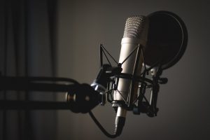 A studio condenser microphone on a boom arm in a podcast studio