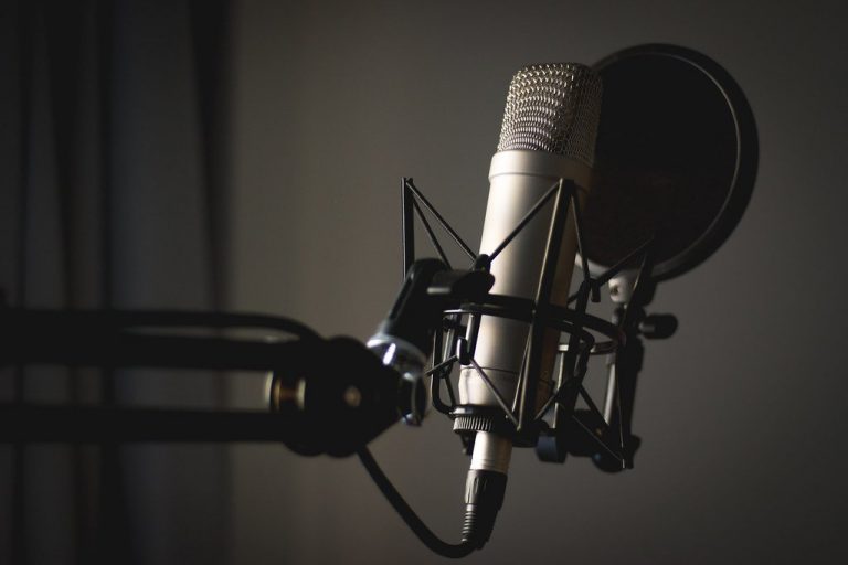 A studio condenser microphone on a boom arm in a podcast studio