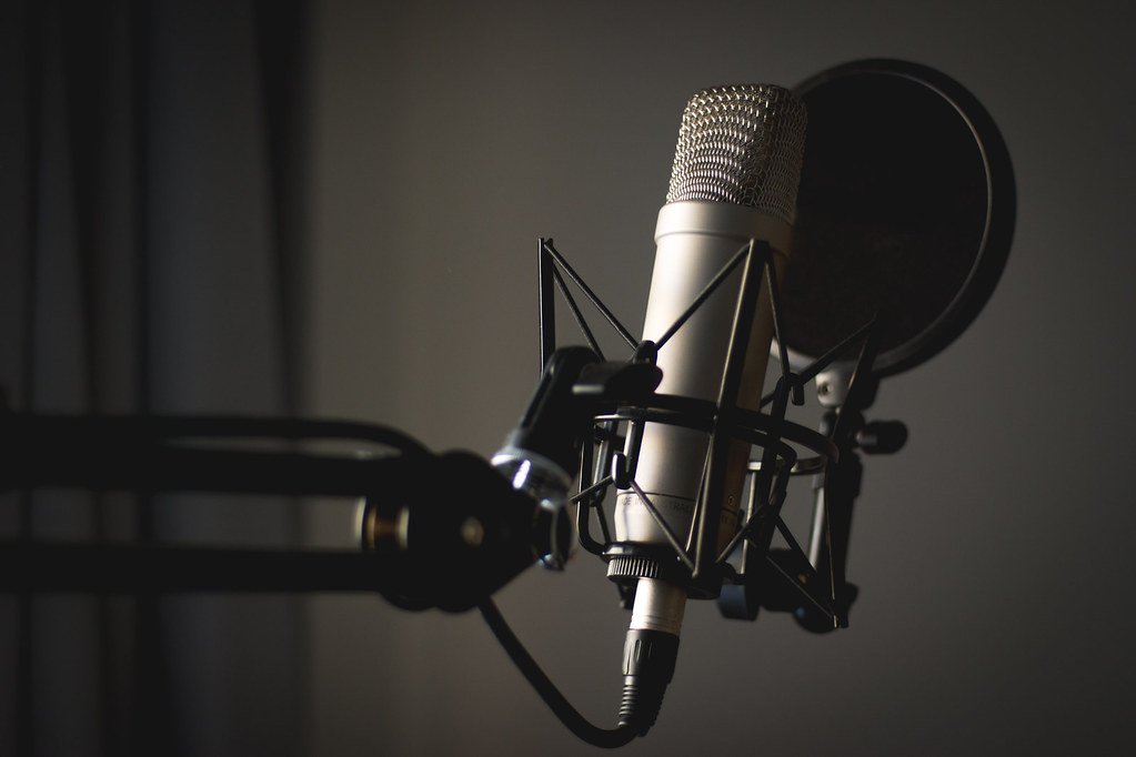 A studio condenser microphone on a boom arm in a podcast studio
